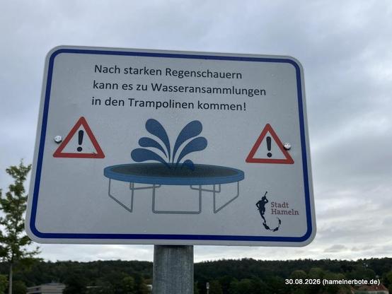 Warnschild: "Nach starken Regenschauern kann es zu Wasseransammllungen in den Trampolinen kommen!"